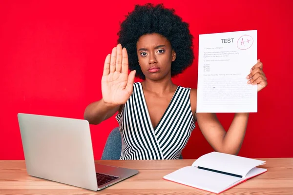 Young african american woman showing a passed exam with open hand doing stop sign with serious and confident expression, defense gesture