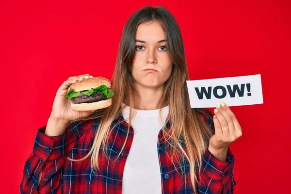 Beautiful Caucasian Woman Eating Tasty Classic Burger Holding Wow Text — Stock Photo, Image