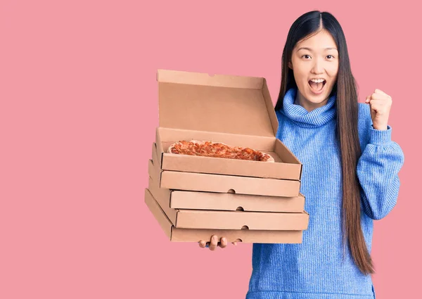 年轻美丽的中国女人举着一盒纸盒意大利披萨 自豪地尖叫着 高举双臂庆祝胜利和成功 — 图库照片