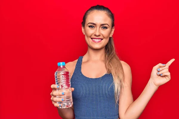 Junge Schöne Blonde Frau Trinkt Flasche Wasser Über Isolierten Roten — Stockfoto