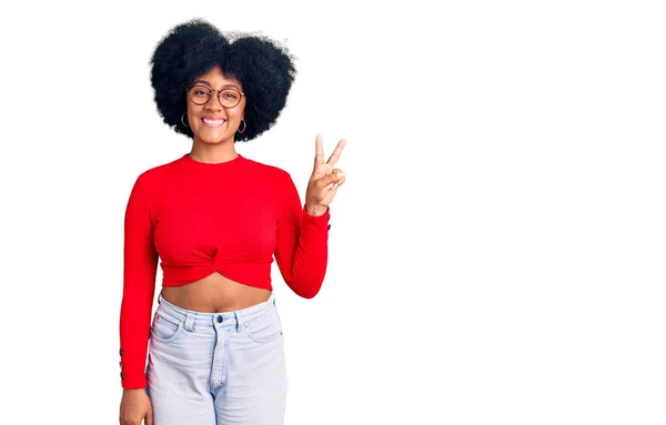 年轻的非洲裔美国女孩 身穿休闲装 戴着眼镜 带着自信和快乐的笑容 用手指着二号手指 — 图库照片