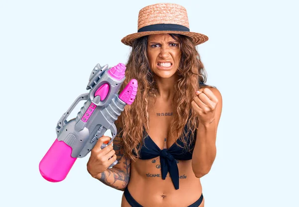 Молодая Латиноамериканка Татуировкой Бикини Шляпе Держащая Водяной Пистолет Раздраженная Разочарованная — стоковое фото