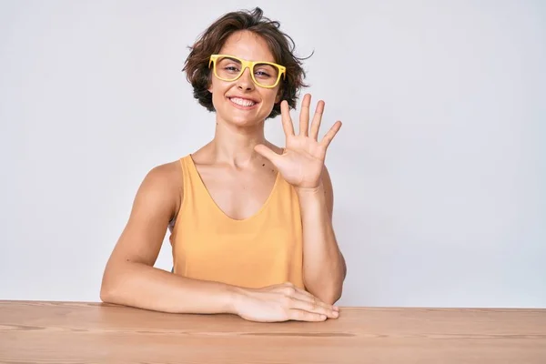 Genç Spanyol Kadın Gündelik Giysiler Gözlük Takıyor Masaya Oturuyor Parmaklarını — Stok fotoğraf