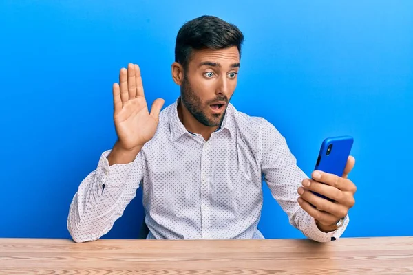 Schöner Hispanischer Mann Der Mit Schockiertem Gesicht Zum Smartphone Winkt — Stockfoto