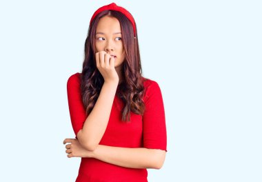 Genç, güzel Çinli bir kız, günlük kıyafetler ve diyabet giyiyor. Stresli ve gergin görünüyor. Elleri ağızdan tırnak yiyor. anksiyete. 