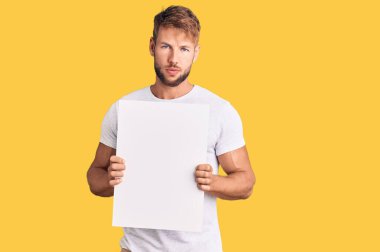 Kafkasyalı genç adam boş afiş tutuyor. Düşünce tarzı ve ayık ifadesi. Kendine güveni tam görünüyor. 