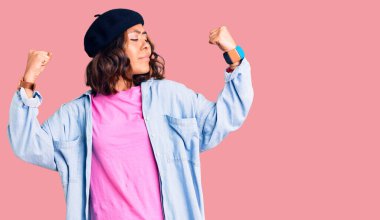 Genç, güzel, melez, Fransız görünümlü, bereli bir kadın. Kollarında gururla gülümseyen kaslar var. fitness konsepti. 