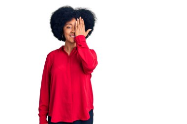 Genç Afro-Amerikan kızı gündelik kıyafetler giyiyor. Bir gözünü eliyle kapatıyor. Yüzünde kendine güvenen bir gülümseme ve sürpriz bir duygu var.. 