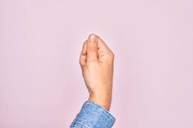 İzole edilmiş pembe arka planda parmaklarını gösteren beyaz bir gencin eli parmak, iş ve reklamla boş bir alan tutuyor.