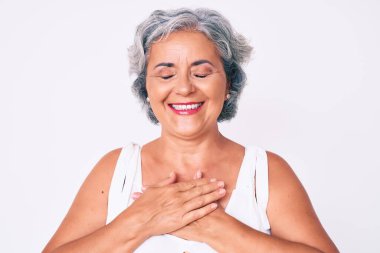 Üst düzey İspanyol kadın gündelik kıyafetler giyiyor. Elleri göğsünde, gözleri kapalı gülümsüyor ve yüzünde minnet ifadesi var. sağlık kavramı. 