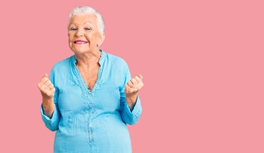 Mavi gözlü, gri saçlı, çok mutlu ve heyecanlı bir son sınıf güzeli kolları havada, gülümseyen ve başarı çığlıkları atan bir jest yapıyor. kutlama konsepti. 