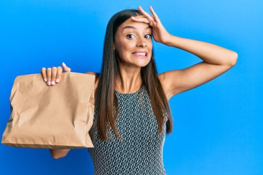 Elinde paket kâğıt poşet tutan genç İspanyol kadın, gergin ve hayal kırıklığına uğramış, şaşırmış ve sinirli bir yüz ifadesi var. 