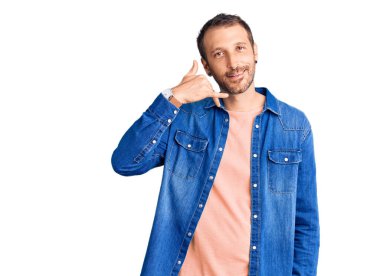 Genç, yakışıklı, sıradan kıyafetler giymiş, gülümseyen, el ve parmaklarıyla telefonla konuşan bir adam. iletişim kavramları. 