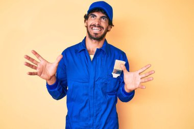 Kıvırcık saçlı ve ayı gibi giyinmiş yakışıklı genç adam. Mimarlı tulum giyiyor. Deli gibi bağırıyor ve agresif bir ifade ve kolla bağırıyor. hüsran kavramı. 