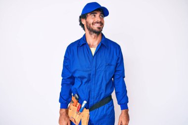 Kıvırcık saçlı ve ayı gibi giyinen yakışıklı bir genç adam yüzünde gülümseme, doğal bir ifade ile yan yana bakıyor. Kendinden emin gülen. 