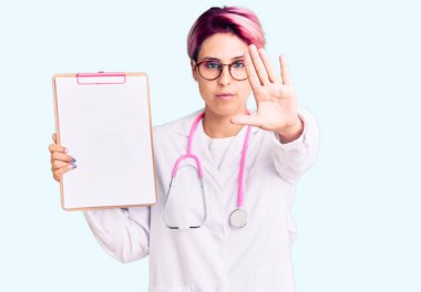 Pembe saçlı, doktor steteskobu takan genç bir kadın. Elinde pano, elinde tıbbi raporla elinde dur işareti, ciddi ve kendinden emin bir ifadeyle savunma jesti yapıyor. 