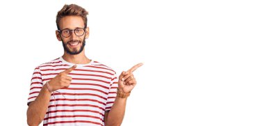 Sakallı, sıradan giyinen, gözlüklü, gülümseyen ve kameraya bakan yakışıklı sarışın bir adam.. 