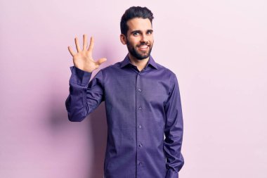 Sakallı, sıradan tişörtlü, genç ve yakışıklı bir adam beş numarayı gösteriyor ve gülümsüyor. Kendinden emin ve mutlu.. 