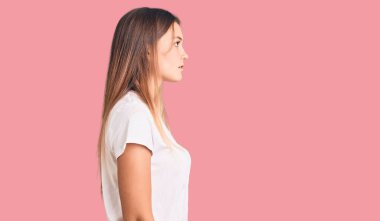 Güzel, beyaz tişört giyen beyaz bir kadın, rahat bir görünüm takınıyor, doğal bir yüzü ve kendine güvenen bir gülüşü var.. 