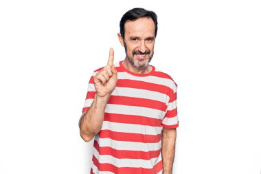 Orta yaşlı, çizgili tişört giyen yakışıklı bir adam izole edilmiş beyaz arka planda duruyor. Bir fikir veya soruyla gülümsüyor ve mutlu bir yüzle işaret ediyor.