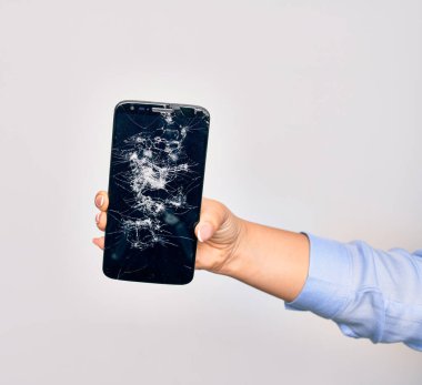 Kırık akıllı telefon tutan beyaz arka planda beyaz ekran görüntüsü olan beyaz bir kadının eli.