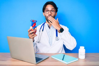 Yakışıklı, doktor üniforması giyen, kalbi ağızla kaplayan, şok olmuş ve hata yapmaktan korkan bir İspanyol. şaşırmış ifade 