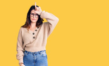 Güzel, genç, esmer bir kadın. Günlük kıyafetler ve gözlük takıyor. Alnında parmakları olan insanlarla dalga geçiyor.. 