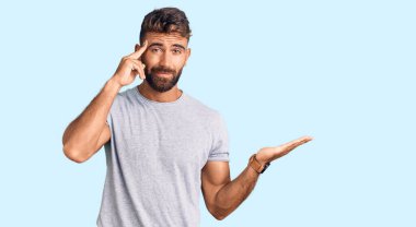 Gündelik giysiler giyen genç İspanyol adam avuç içi açık fotokopi alanı gösterip alnını işaret etmekten rahatsız oluyor. Bunu bir düşün.. 