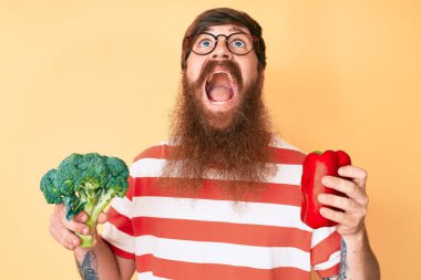 Uzun sakallı, elinde brokoli ve kırmızı biber olan yakışıklı, genç, kızıl saçlı bir adam. Kızgın ve öfkeli çığlıklar atıyor. Öfkeyle bağırıyor.. 