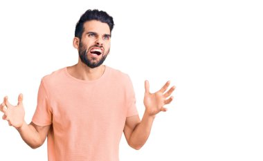 Sakallı, sıradan tişörtlü, deli gibi bağıran, sinirli ifadeli ve kollarını kaldırmış genç yakışıklı bir adam. hüsran kavramı. 