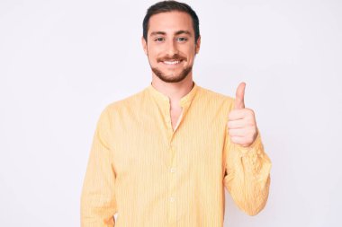 Gündelik kıyafetler giyen, mutlu ve pozitif gülümseyen, mükemmel ve onay işareti yapan genç yakışıklı bir adam. 