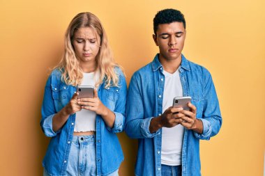 Akıllı telefonları kuşkucu ve gergin kullanan ırklar arası genç çift sorun yüzünden surat asıyor. negatif kişi. 