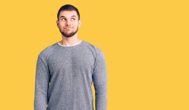 Genç, yakışıklı, sıradan bir süveter giyen, gülümseyen, yan bakan ve düşünen bir adam.. 