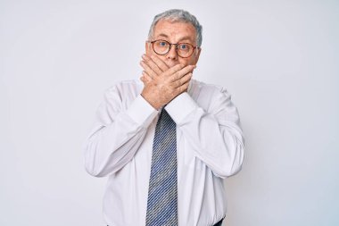 İş kıyafetleri giyen yaşlı gri saçlı adam yanlışlıkla ağızlarını kapatarak şok geçirdi. gizli kavram. 