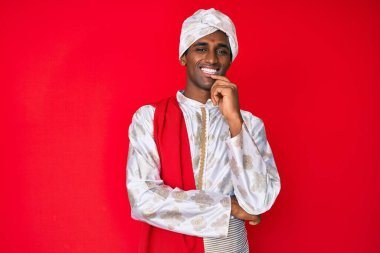 Gelenek giyinmiş yakışıklı Hintli adam Sherwani sari elbisesi giyiyor kameraya kendinden emin bakıyor kollarını kavuşturup gülümseyerek ve çenesini kaldırarak. Olumlu düşünmek. 