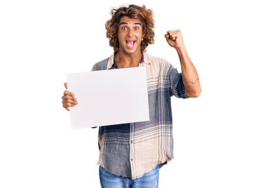 İspanyol asıllı genç adam boş bir pankart tutuyor gururla bağırıyor, zaferi kutluyor ve başarıyı kollarını kaldırarak kutluyor. 