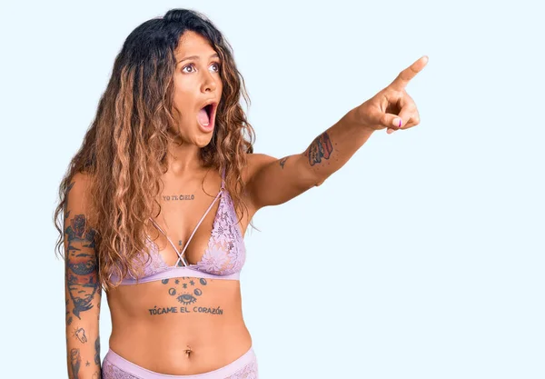 Young Hispanic Woman Tattoo Wearing Lingerie Pointing Finger Surprised Ahead — Stock Photo, Image