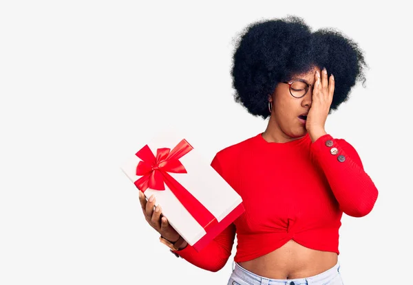 Joven Afroamericana Americana Sosteniendo Regalo Bostezando Cansada Cubriendo Media Cara —  Fotos de Stock