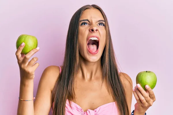 Mujer Hispana Joven Sosteniendo Manzanas Verdes Enojada Loca Gritando Frustrada —  Fotos de Stock
