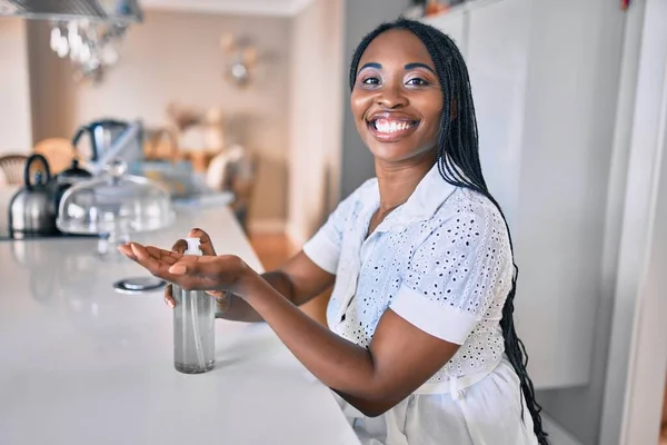 Young african american woman smiling happy using sanitizer hand gel at home