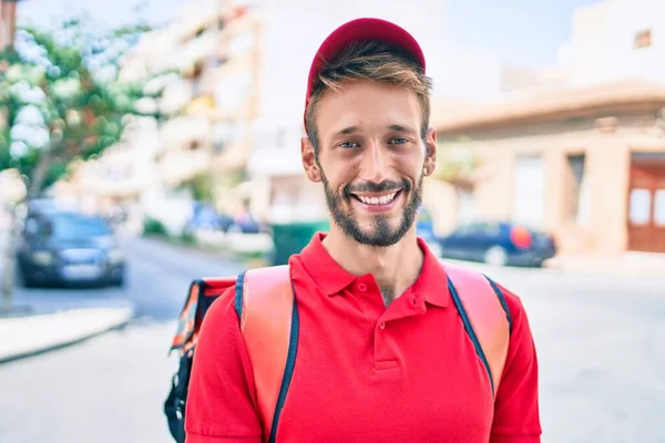 Caucasian delivery man wearing red uniform and delivery backpack smilly happy outdoors