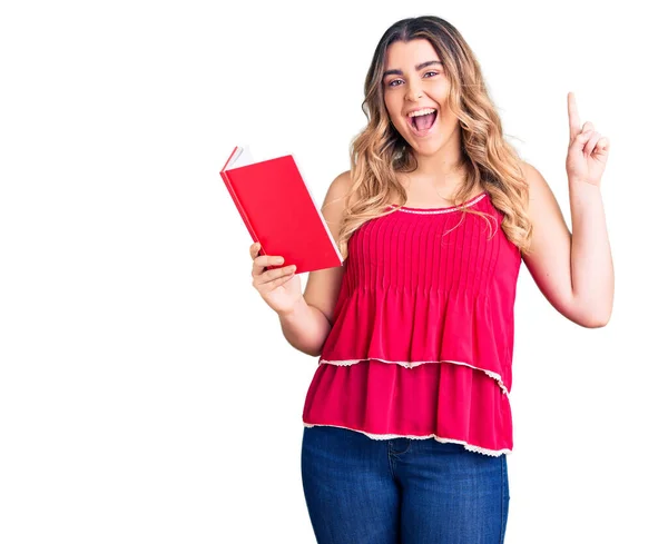 Jovem Caucasiana Segurando Livro Surpreso Com Uma Ideia Pergunta Apontando — Fotografia de Stock