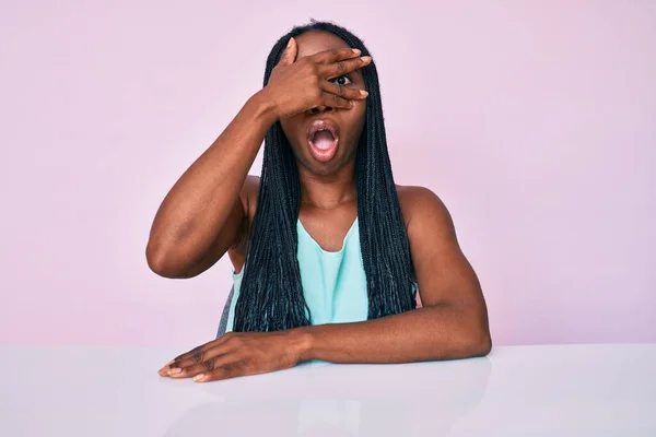 African American Woman Braids Wearing Casual Clothes Sitting Table Peeking — Stock Photo, Image