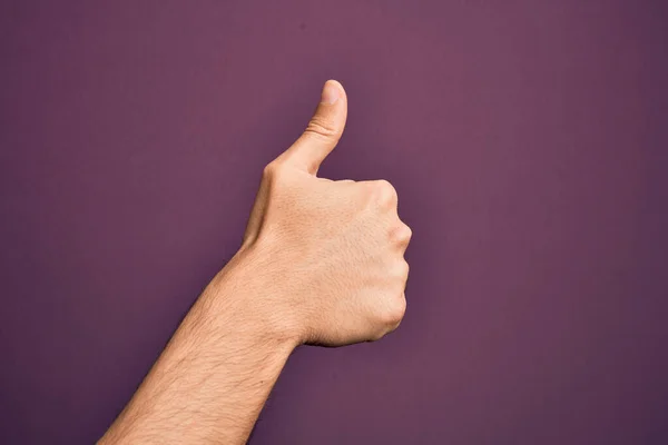 在孤立的紫色背景上伸出手指的高加索年轻人的手 手举着大拇指 做着成功的认可手势 验证和积极的符号 — 图库照片