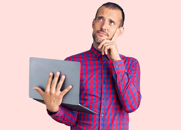 若いハンサムな男は コンピュータのラップトップの深刻な顔を使用して作業顎に手で質問について考えて 混乱のアイデアについて思慮深い — ストック写真