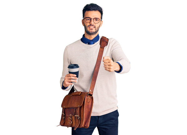 Young handsome hispanic man wearing leather bag and drinking take away coffee annoyed and frustrated shouting with anger, yelling crazy with anger and hand raised 