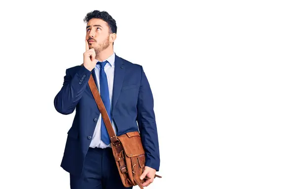 Young Hispanic Man Wearing Suit Leather Bag Serious Face Thinking — Stock Photo, Image