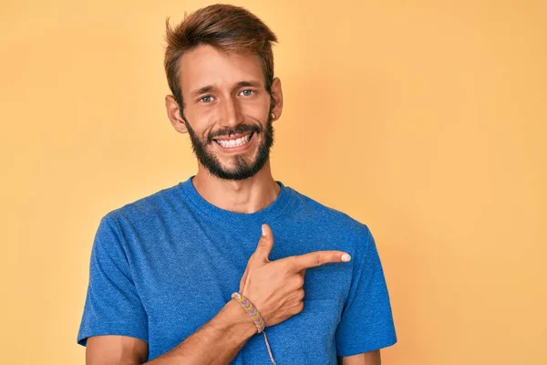 Handsome caucasian man with beard wearing casual clothes cheerful with a smile of face pointing with hand and finger up to the side with happy and natural expression on face