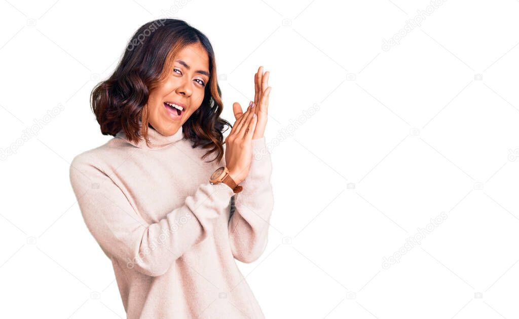 Young beautiful mixed race woman wearing winter turtleneck sweater clapping and applauding happy and joyful, smiling proud hands together 