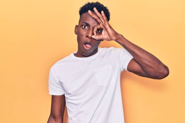 Genç Afro-Amerikan bir adam günlük giysiler giyiyor. Şaşırmış yüz ifadesiyle şaşırmış, parmaklarının arasından bakıyor. İnançsız ifade. 